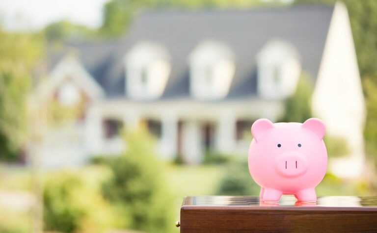 Real estate sale, home savings, loans market concept. Housing industry mortgage plan and residential tax saving strategy. Piggy bank isolated outside home on background. Focus on piggybank