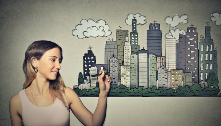Woman drawing city skyline on grey wall background